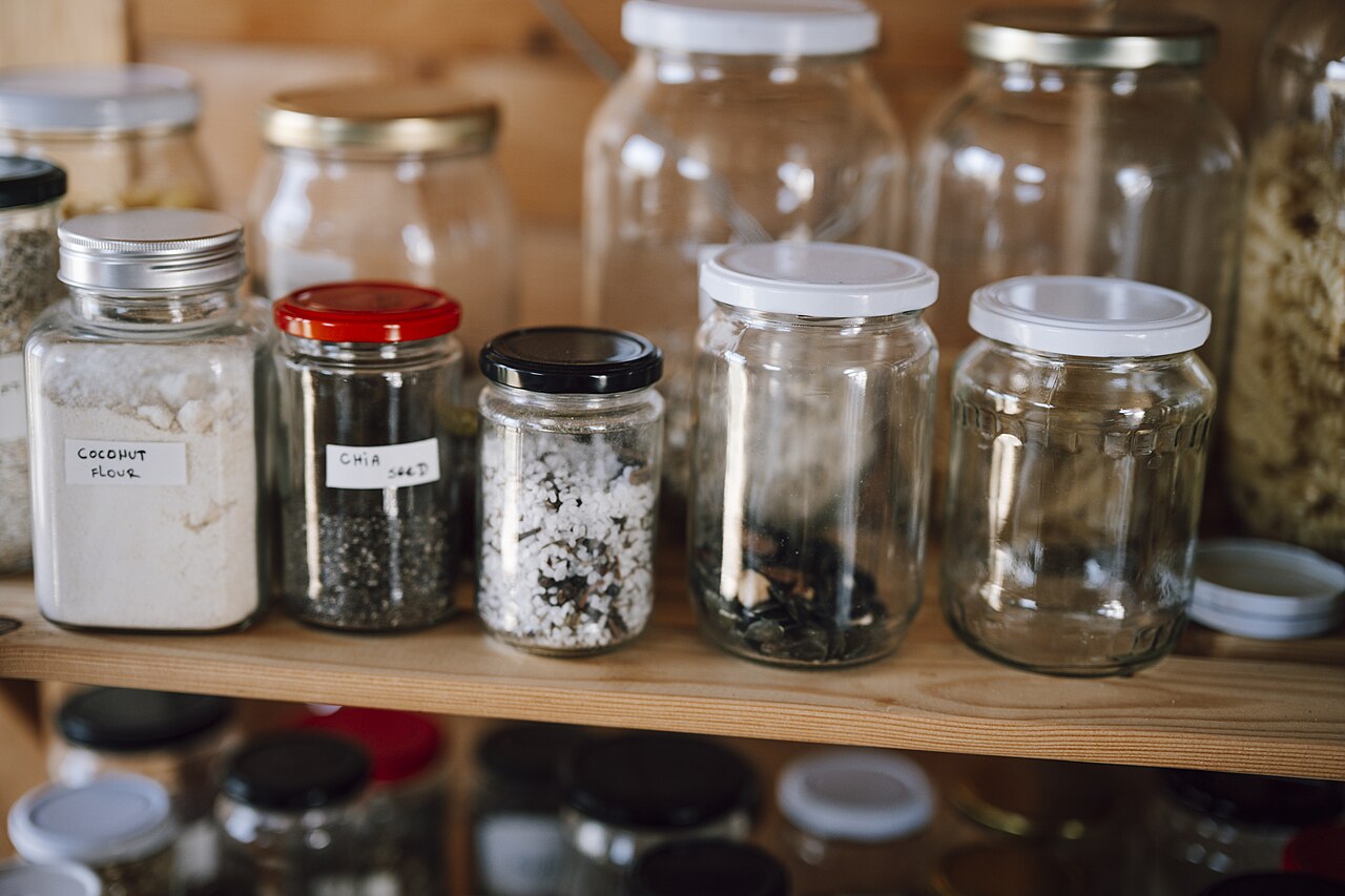 Partly filled labeled jars on a pantry shelf